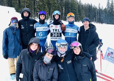 A group of ski athletes post for a picture at the bottom of the mountain.