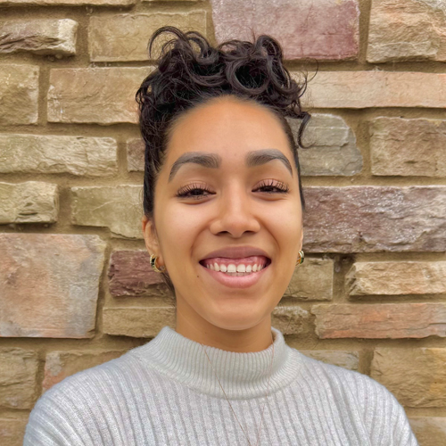 A woman with blond hair in front of a white background.