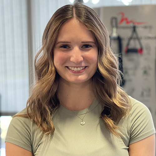 A woman with blond hair in front of a white background.